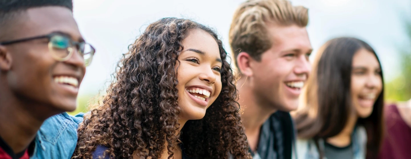 A group of smiling young people, laughing and looking to the right