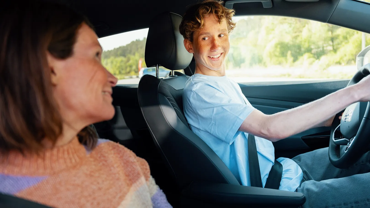 A learner driver at the wheel, glancing over at the supervising adult in the passenger seat