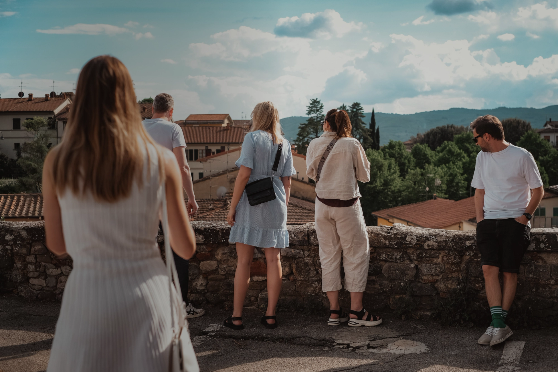 Colleagues taking in the view over an Italian hill town from a stone wall on a company trip.