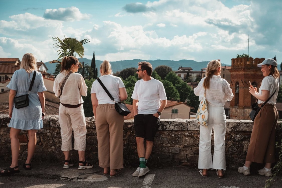 Colleagues on a trip together, looking out over a Tuscan hill town from a stone wall.