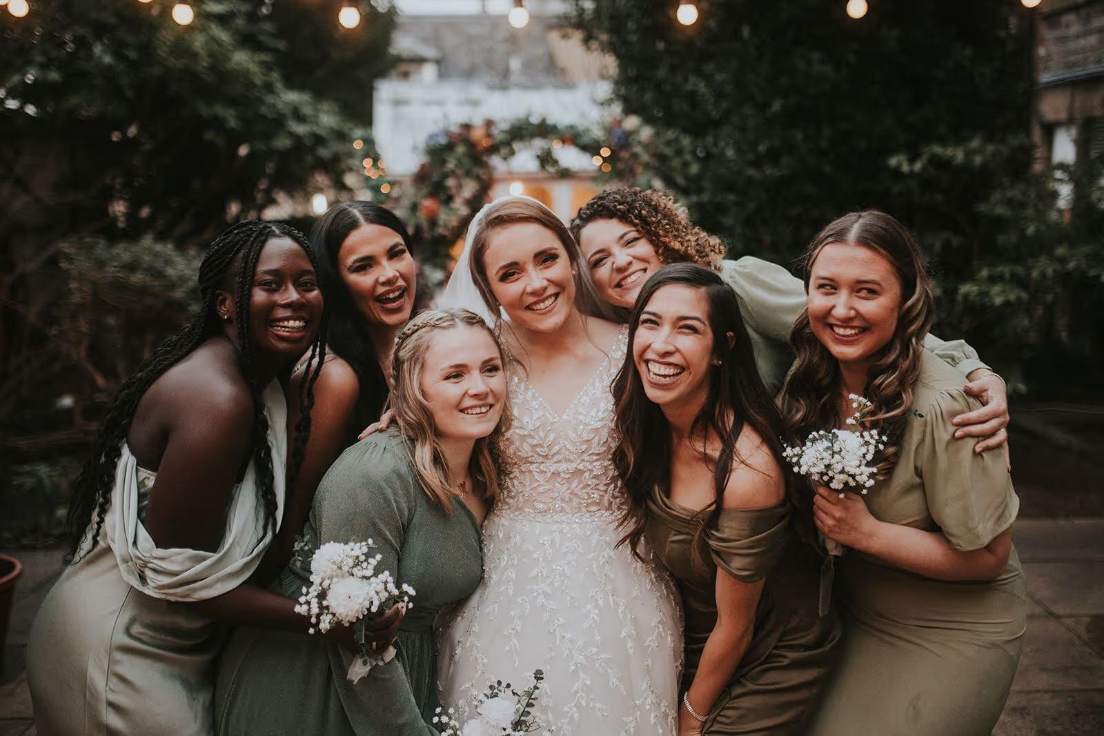 Bride laughing with her bridesmaids in green dresses