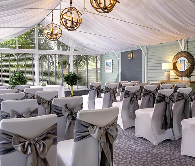Conservatory set for a wedding ceremony, with chairs dressed in grey sashes