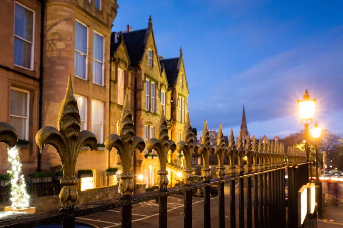 The hotel's front at dusk with the street lamps lit