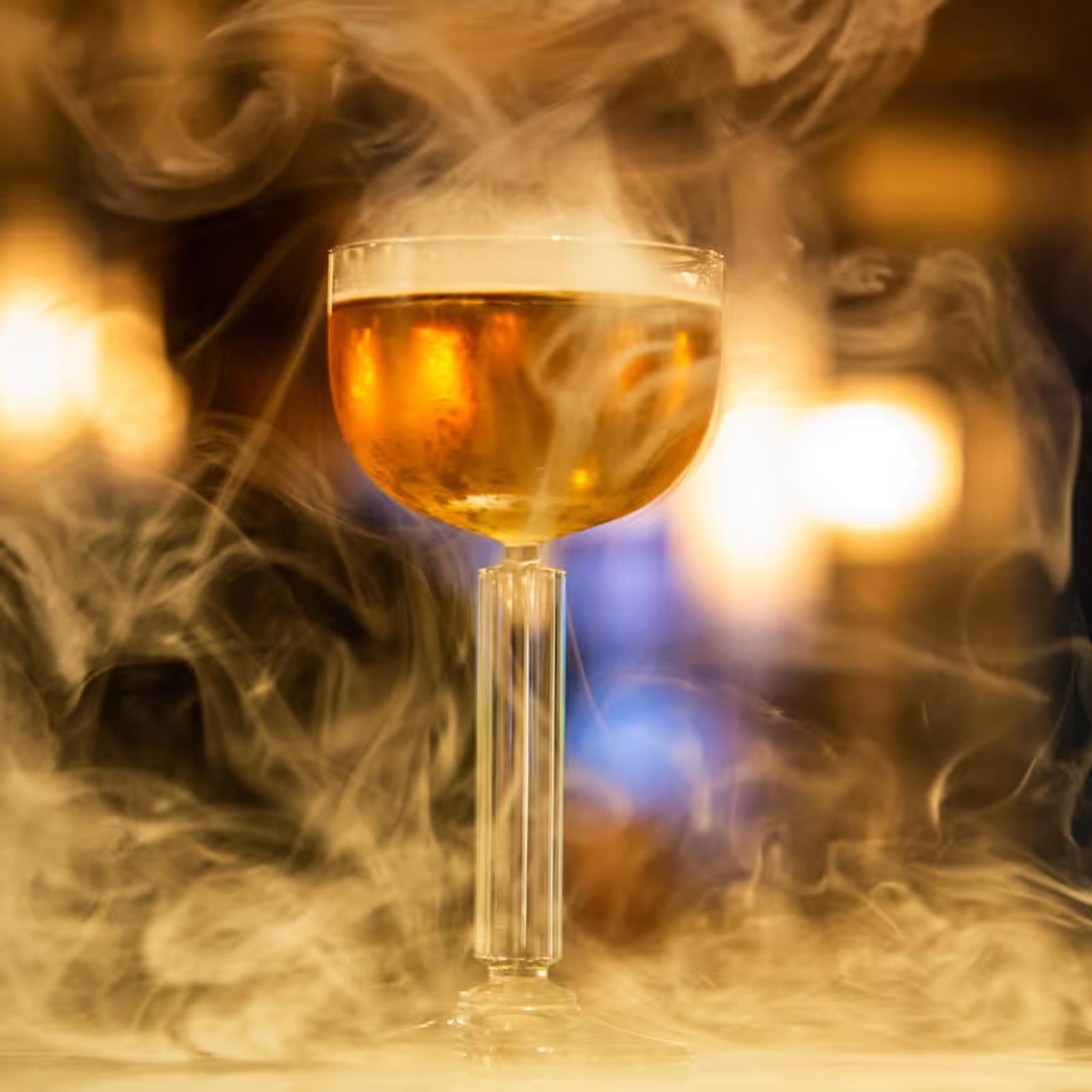 Cocktail in a coupe glass with smoke swirling around it