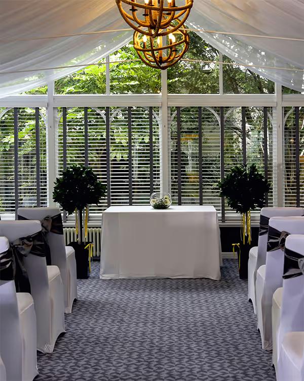 Conservatory ceremony room with white chairs either side of the aisle