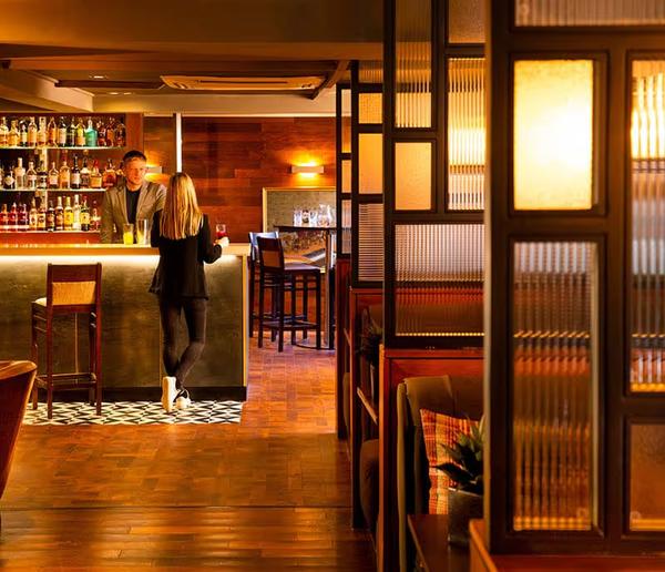 Guests at the bar beyond the wooden booths