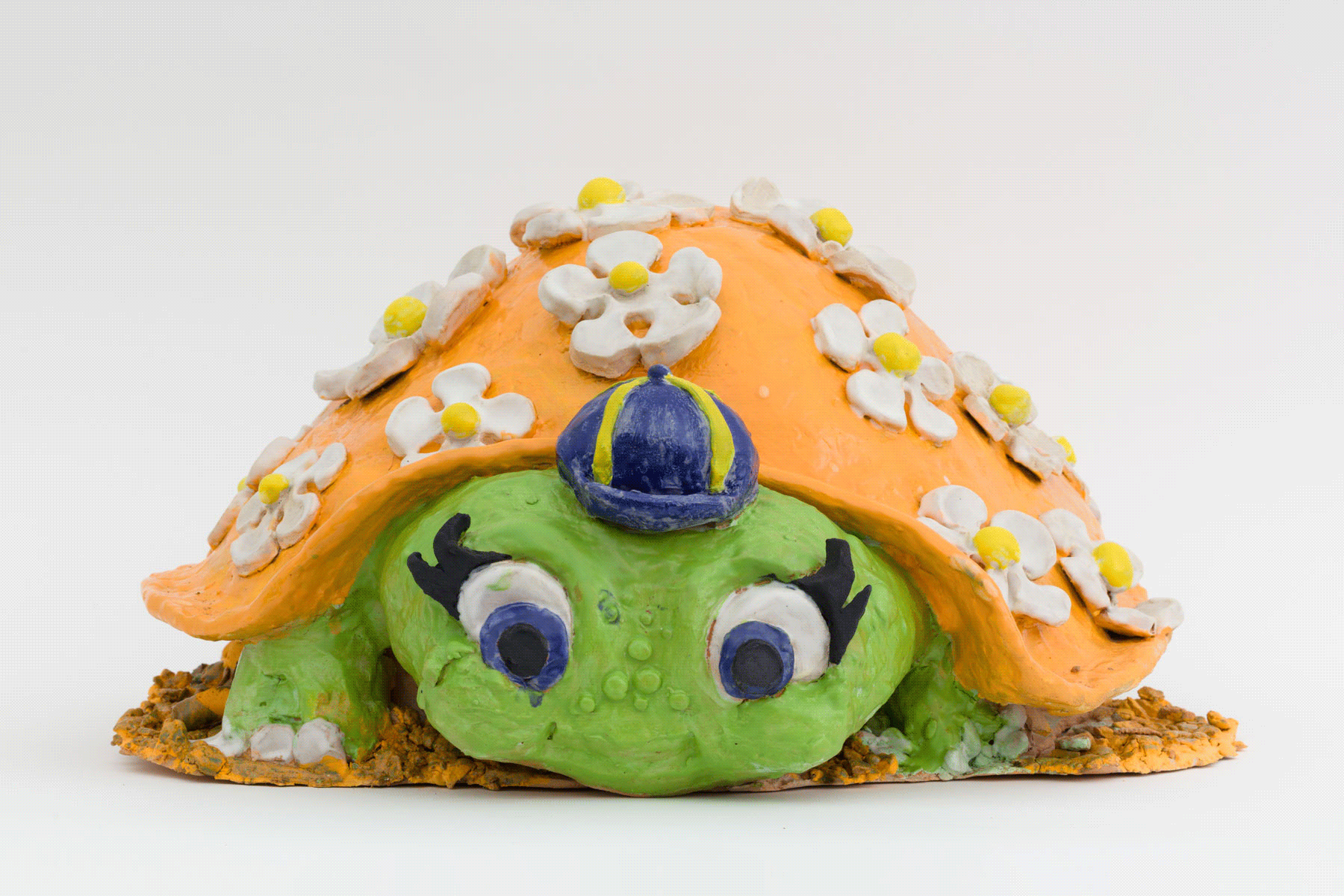 An orange and green ceramic turtle covered in flowers, spinning between four different views.