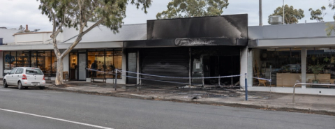 Blackened shopfront cordoned off with tape between neighbouring shops.