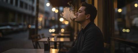 Man sits outside a cafe vaping