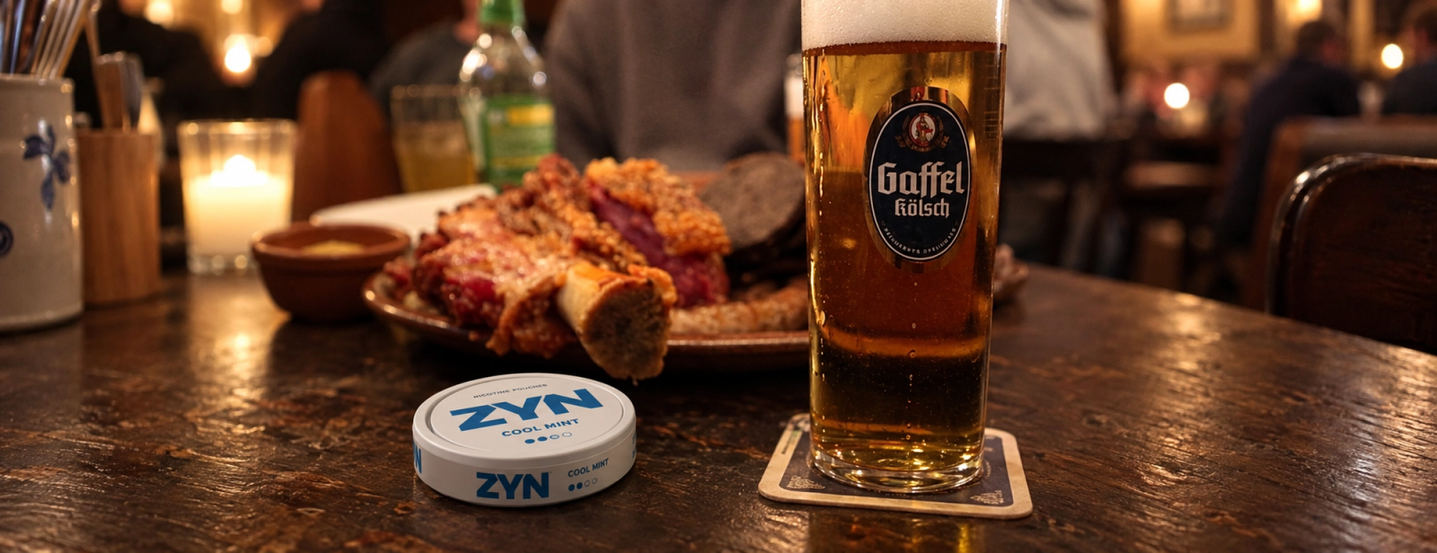 A Zyn nicotine pouch tin beside a glass of beer and a meal on a restaurant table.