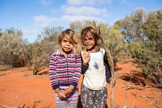 Two kids smiling and waving toward the camera