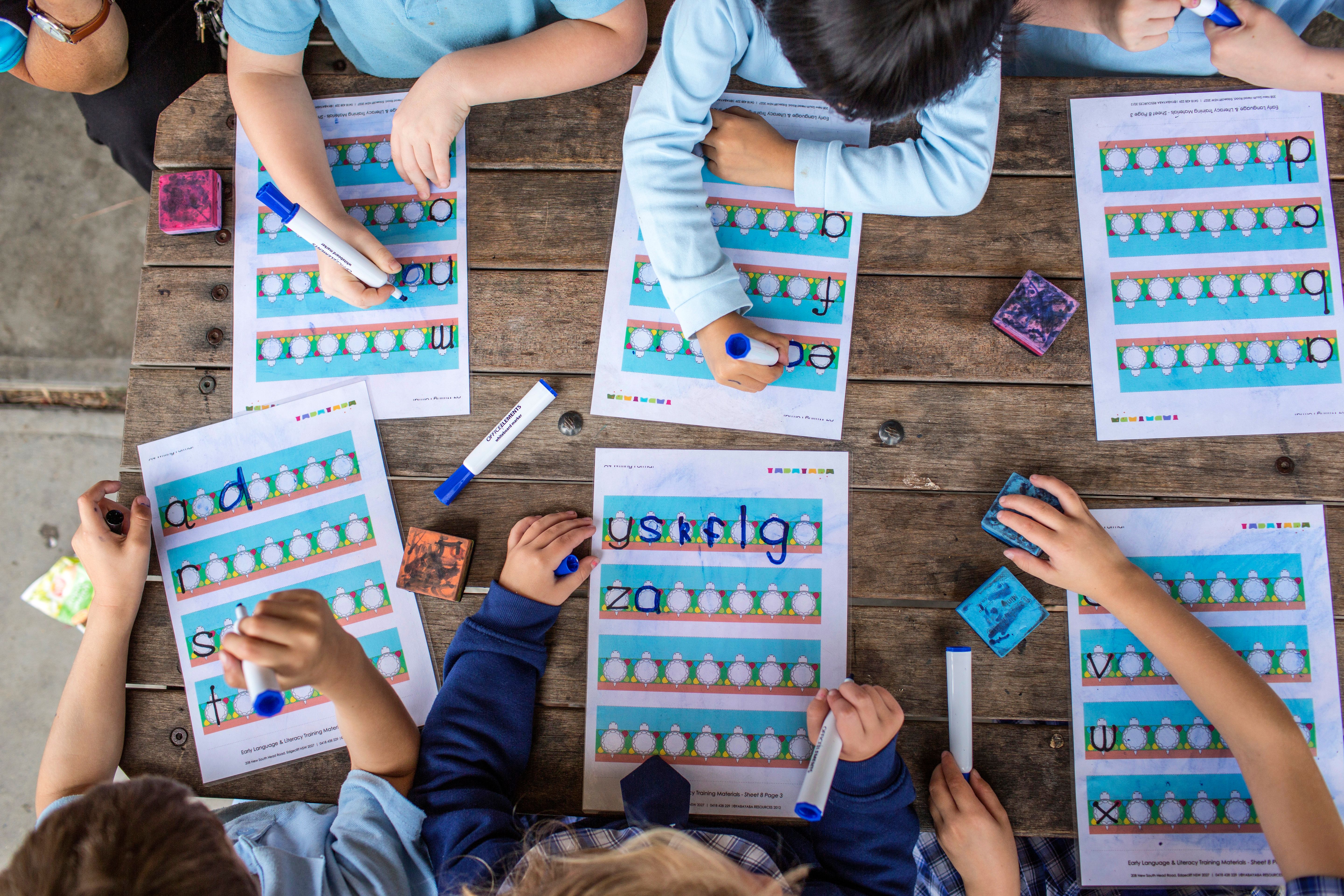 Top down photo of children working on spelling workbooks