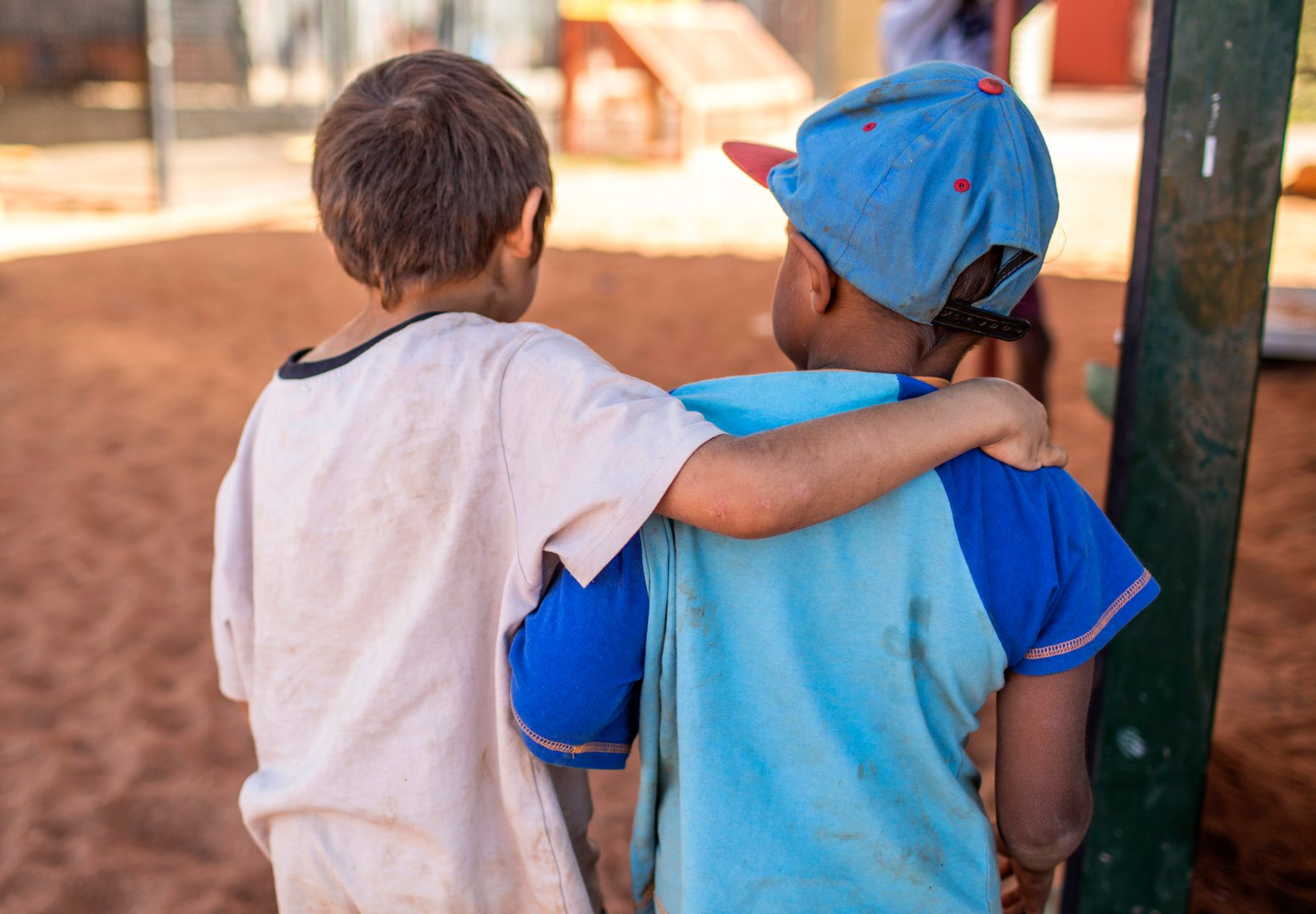two kids facing away from the camera, arms over each others shoulders