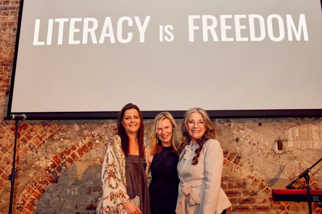 Two children facing away from the camera, one arm over the shoulders of the other child.