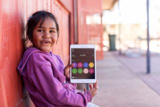 A child holding a tablet with some educational games shown on screen