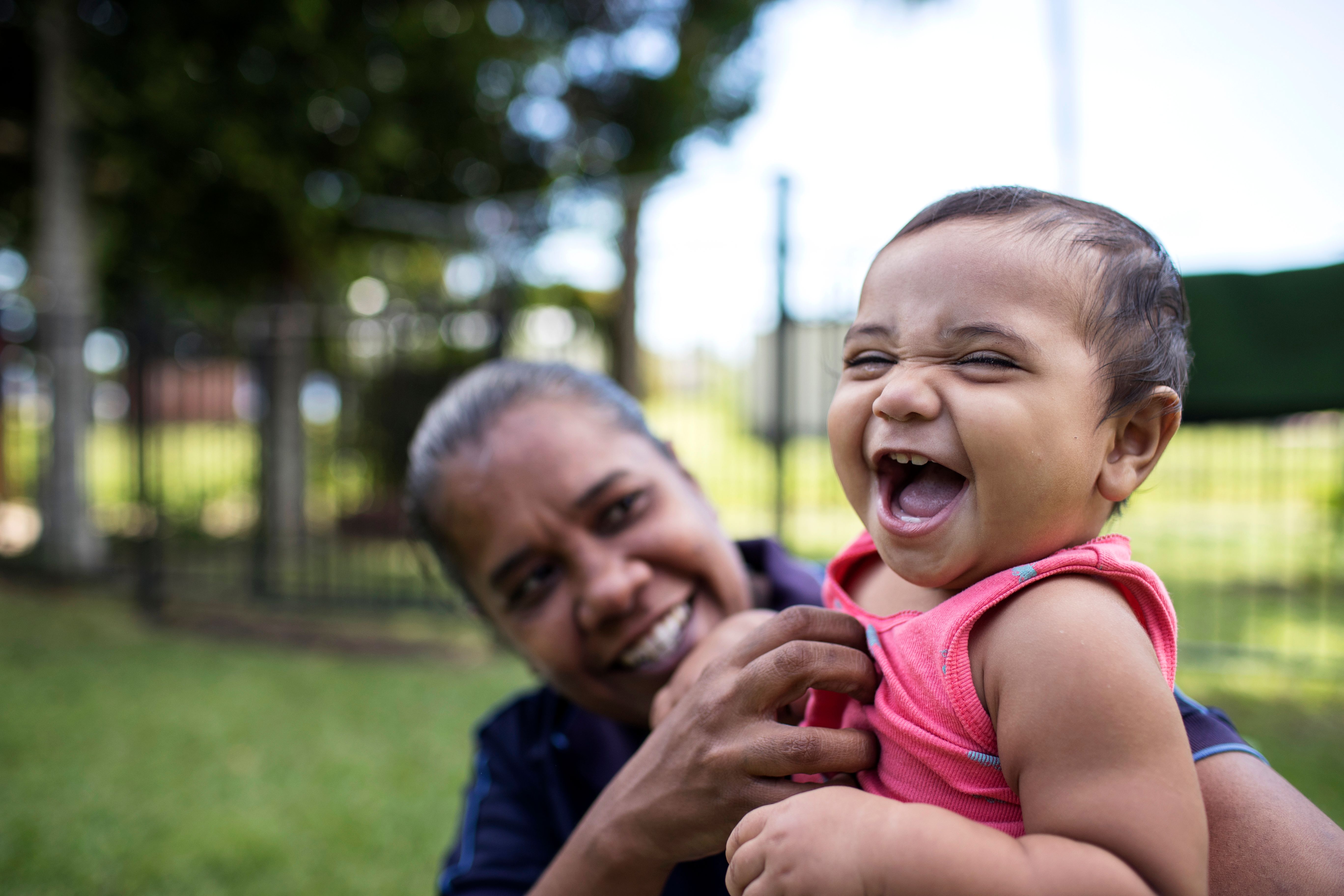 a child being held up to the camera laughing and smiling