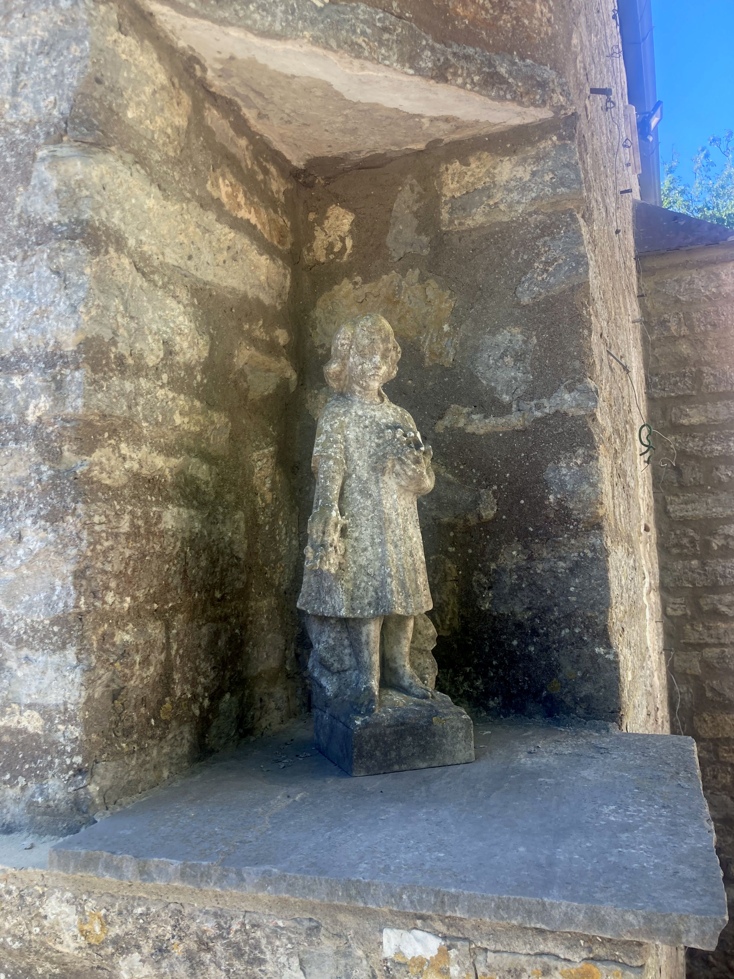 Small stone statue set into a wall of a girl