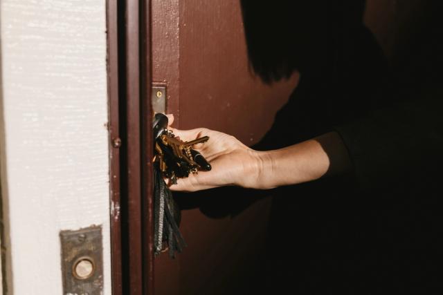 Person låser seg inn en dør med nøkler. Foto.