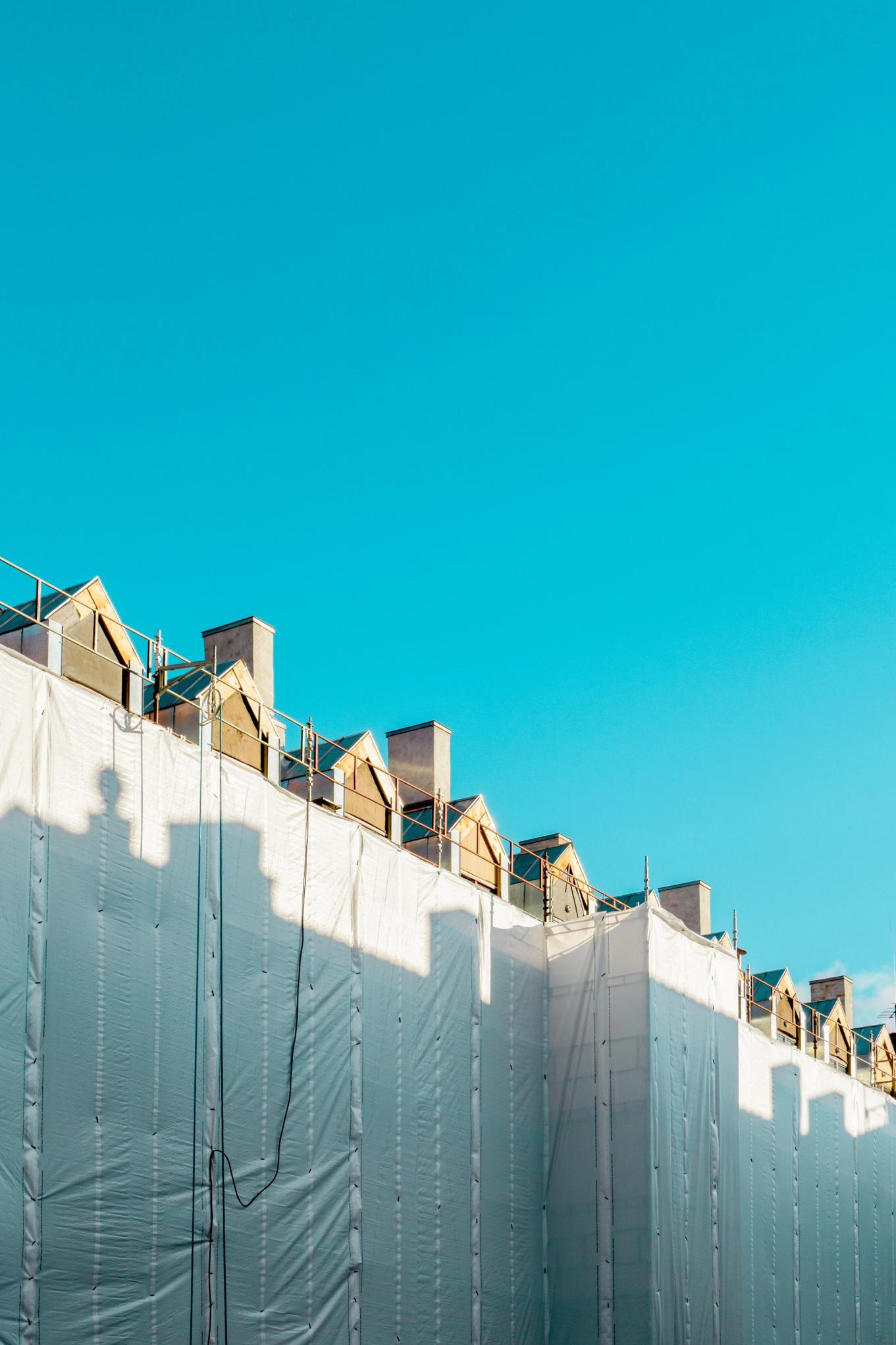 Bygning er skjult av byggearbeid. Blå himmel. Foto.