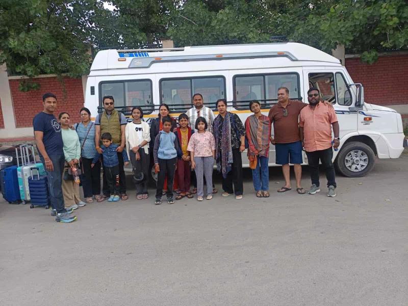 Xogul, one of the top 10 travel agents in Kashmir, with a family group beside a tempo traveller