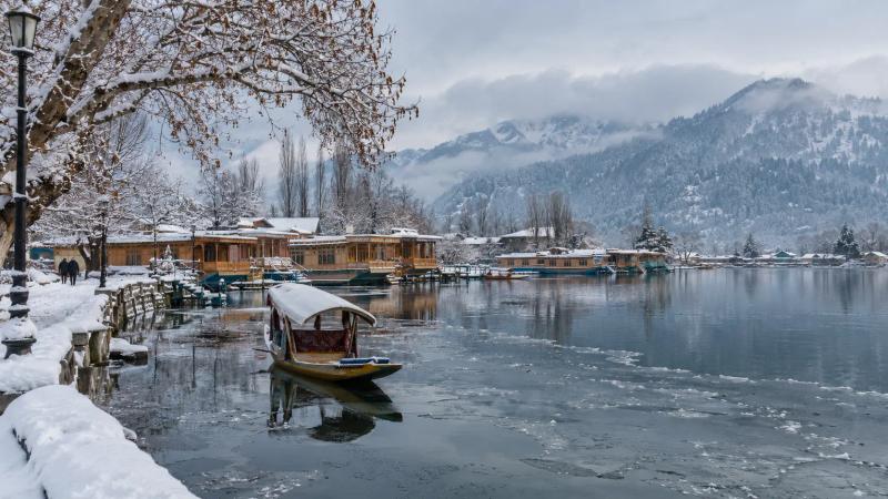 Snow-covered houseboats and a traditional shikara on Dal Lake during Kashmir in January