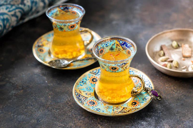 Kashmir winter food and culture featuring traditional saffron tea served in ornate glass cups with decorative saucers.