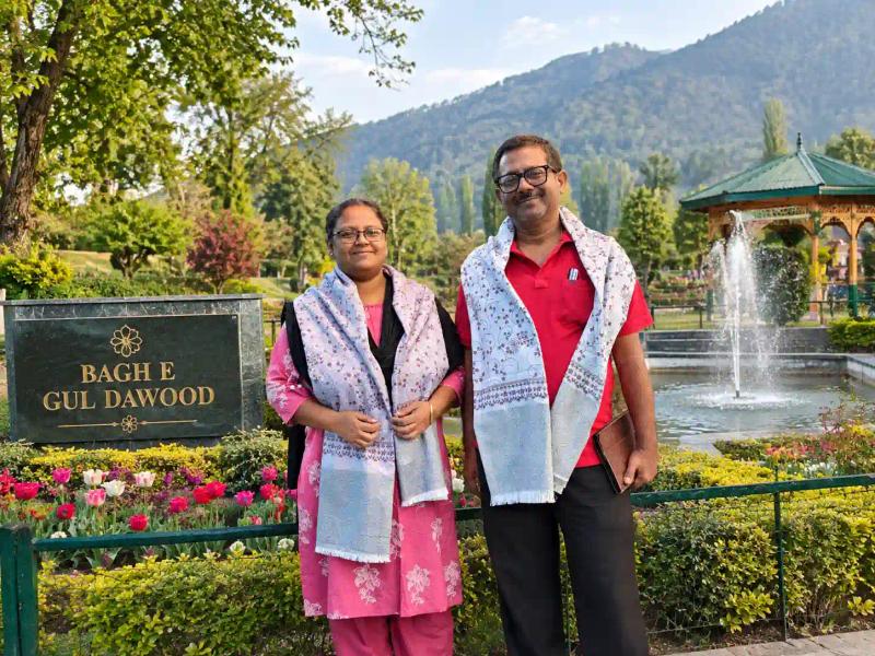 Visitors posing at the Bagh-e-Gul-e-Dawood Srinagar name board with flower beds, a fountain and a gazebo