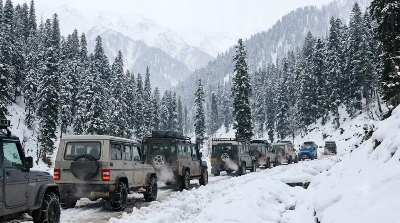A convoy of 4x4 tourist vehicles traversing a snow-covered mountain road, coordinated by the best local tour operator in Kashmir during heavy winter.