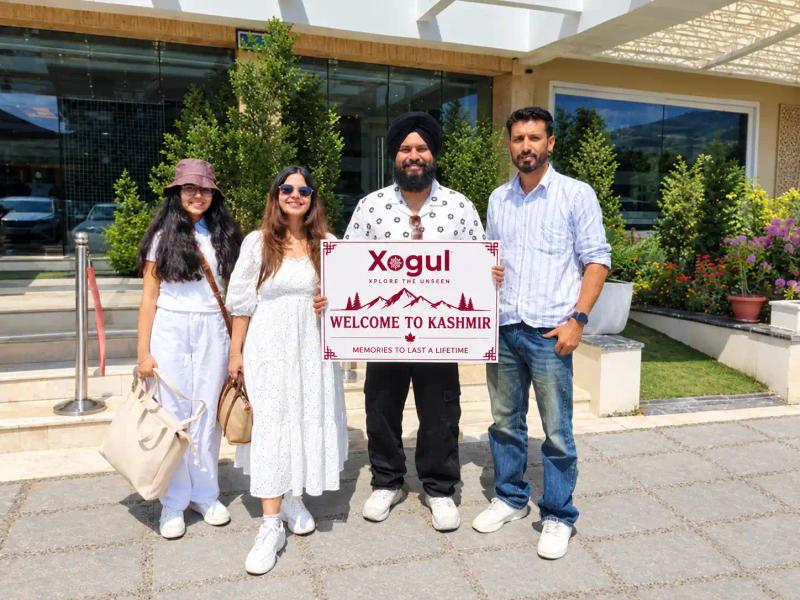 Xogul welcome board held by guests at a hotel entrance, one of the Kashmir tour operators for family trips
