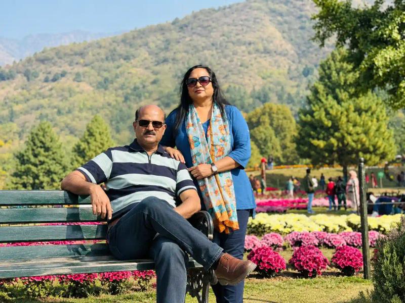 Couple relaxing on a bench beside chrysanthemum beds at Bagh-e-Gul-e-Dawood in Srinagar