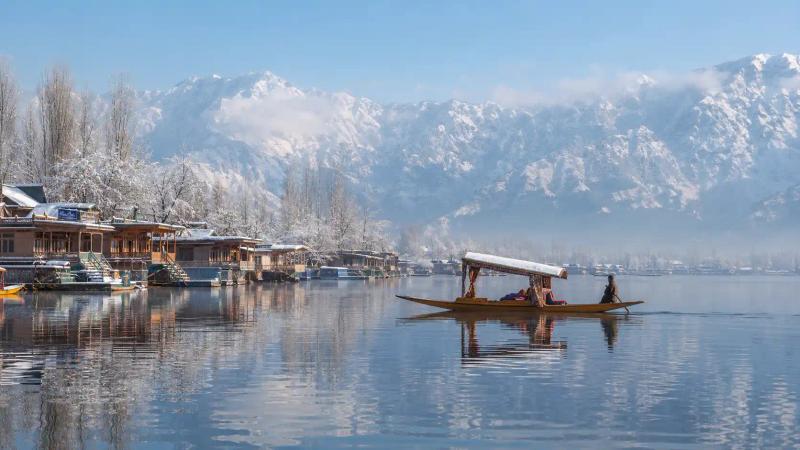 Kashmir in December with a Shikara on Dal Lake and snow-covered mountains in Srinagar