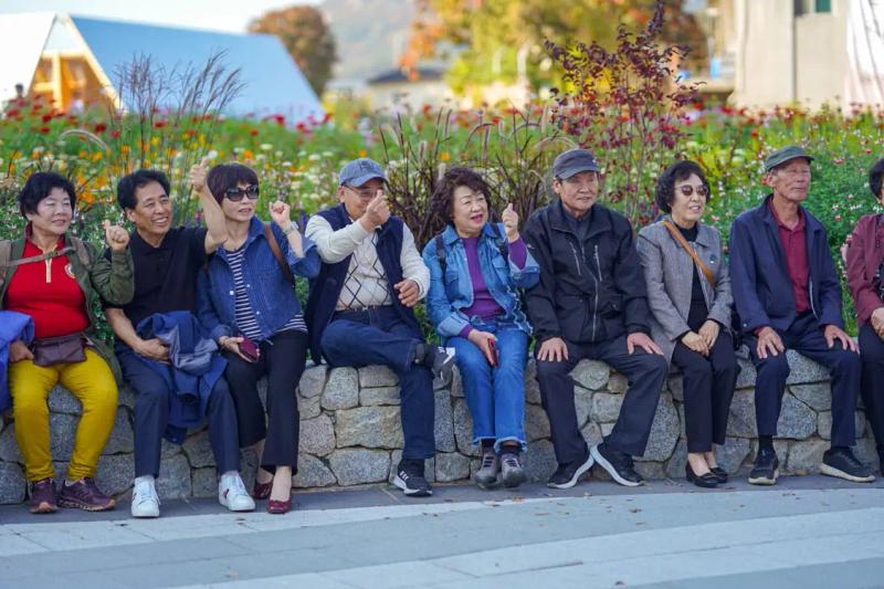 Happy senior citizens group posing near a flower garden, ideal for a Kashmir Tour for Senior Citizens