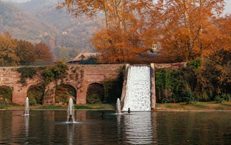 waterfall cascade and fountains at Nishat Bagh Srinagar, with a brick arched wall and autumn chinar trees