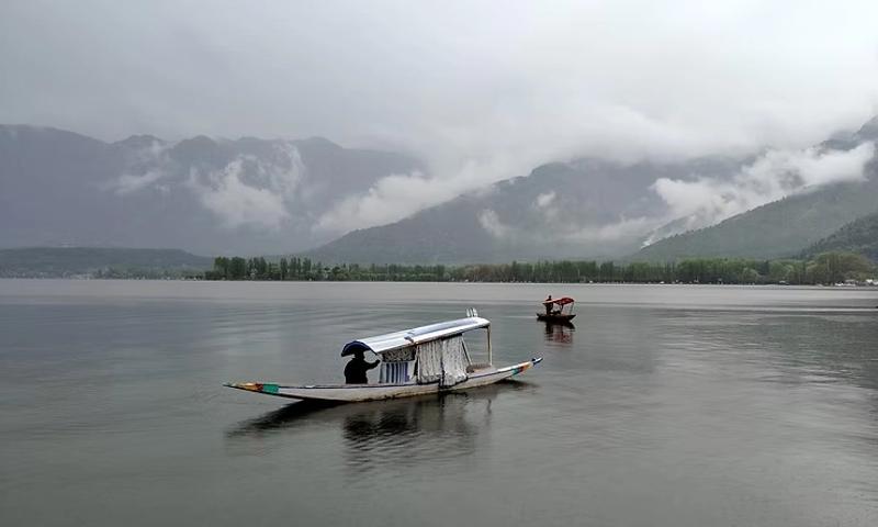 Traditional shikara boat gliding through Dal Lake, with the stunning Himalayan peaks reflected in the tranquil waters.