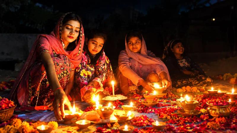 Devotees lighting clay diyas on the ground at night during Diwali in Kashmir
