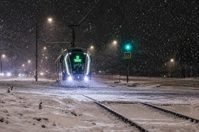 Train moving through heavy snowfall past snow-covered houses, a winter scene for Vande Bharat Srinagar in winter travel