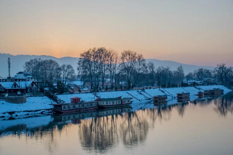 Snow-covered houseboats at sunset in Srinagar, a calm base for Kashmir Winter Packages