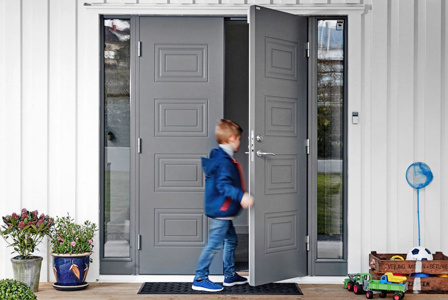 Ung gutt som går inn gjennom en grå Diplomat-dør