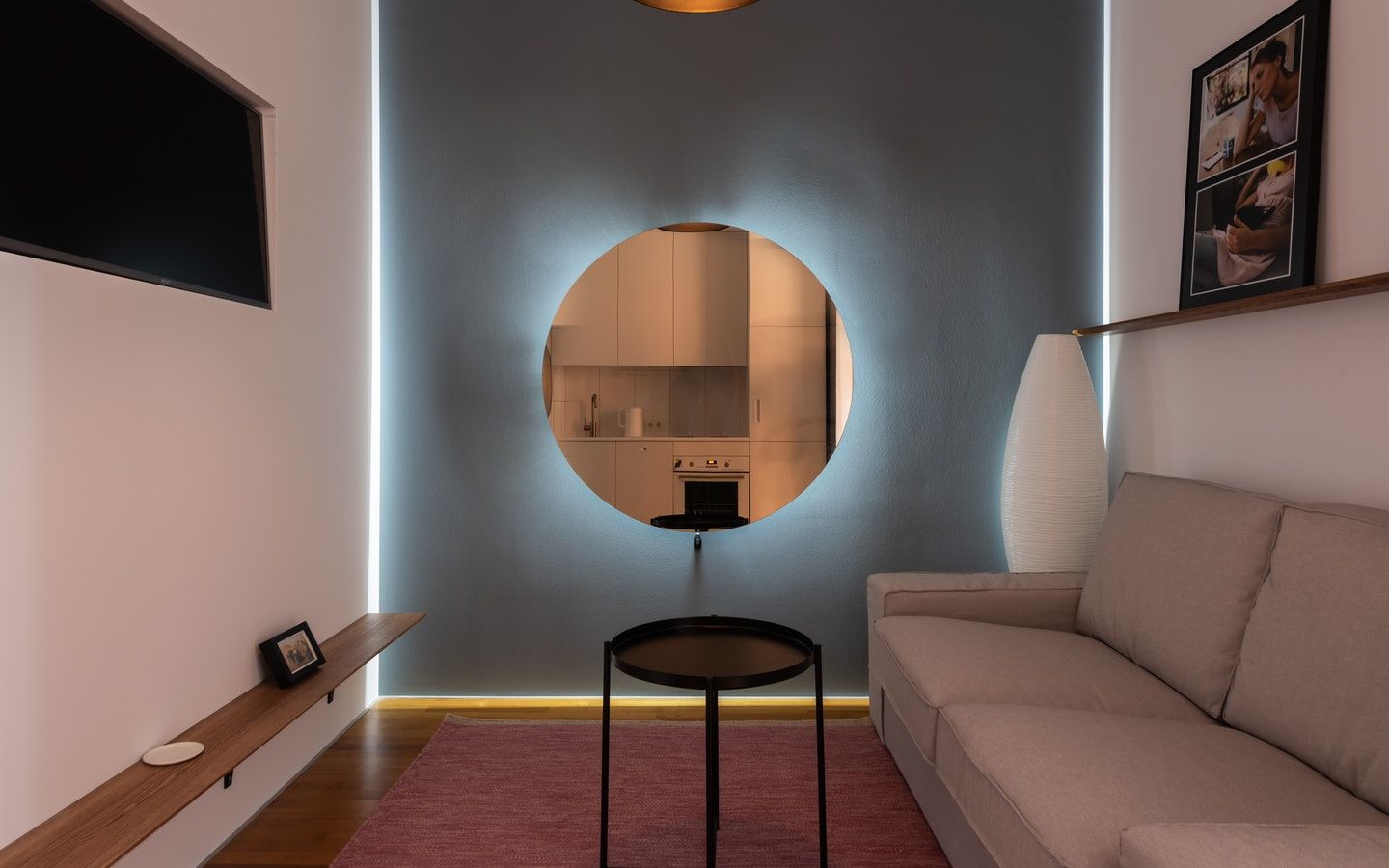 Lekker speilinstallasjon med et rundt speil på en blå vegg med lys bak speilet