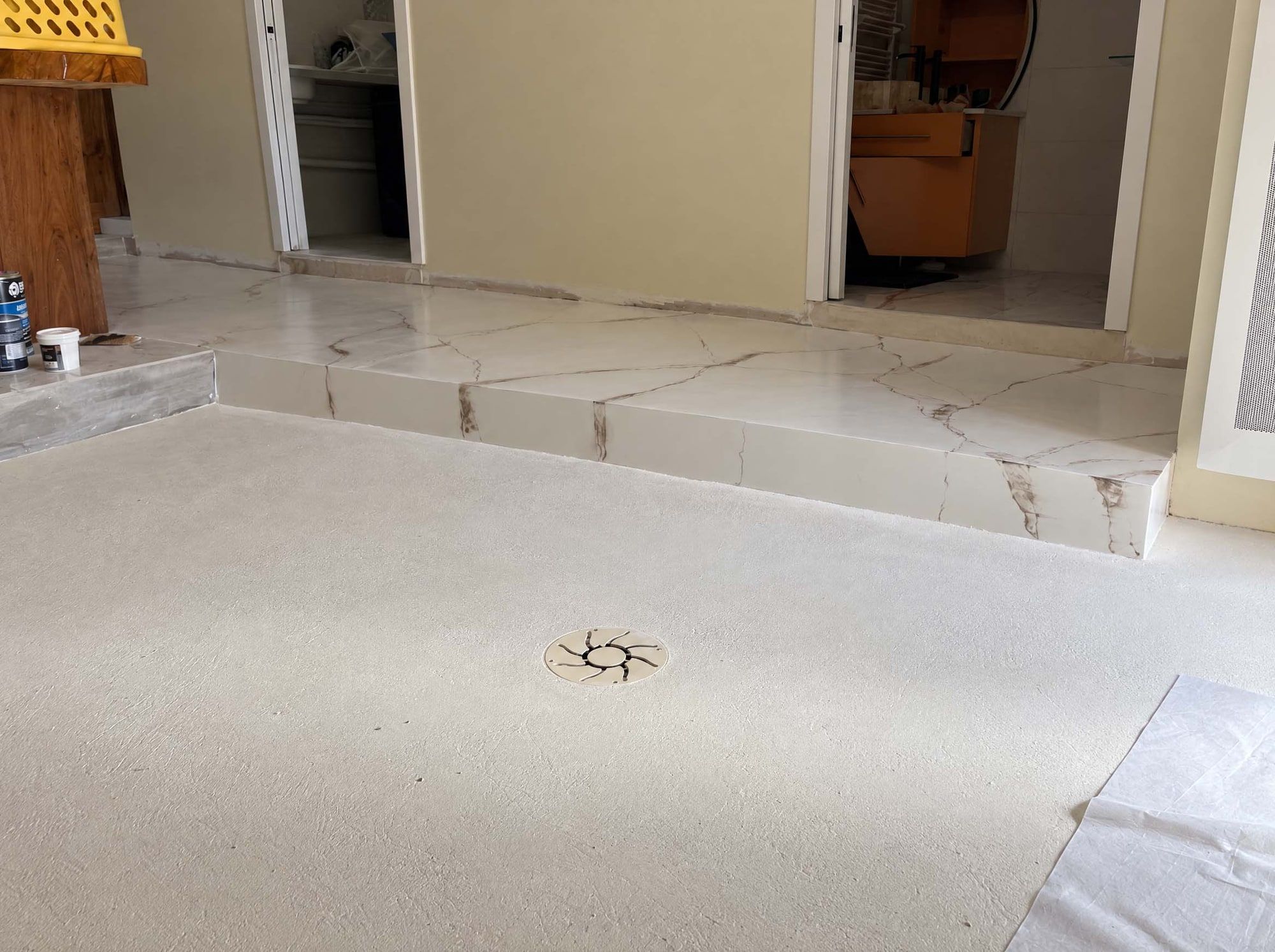 Sol en béton ciré minéral crème sans joint et marche en décor marbre peint à la main, séjour d’une maison au Mas-d’Agenais (47)