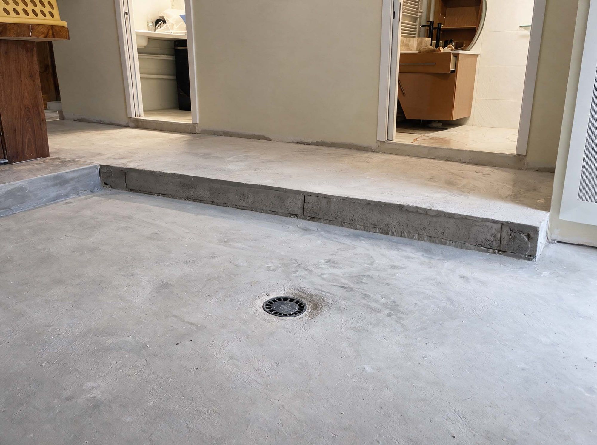 Chape béton brute poncée à nu dans le séjour, avec la bonde de sol au centre, avant la pose du béton ciré, Le Mas-d’Agenais (47)