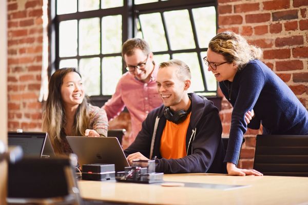 Commure employees gathered around a laptop