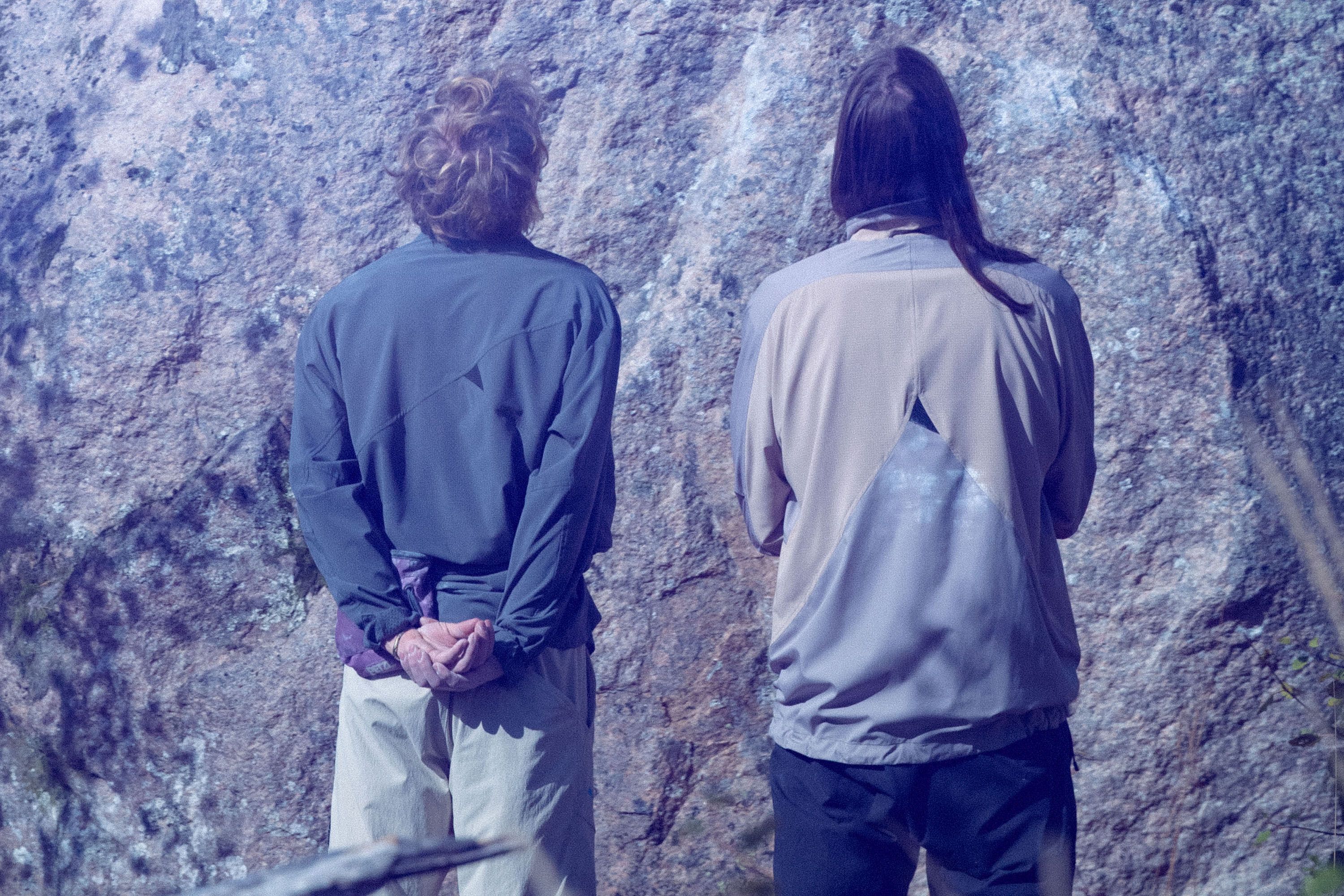 Two man standing before a boulder