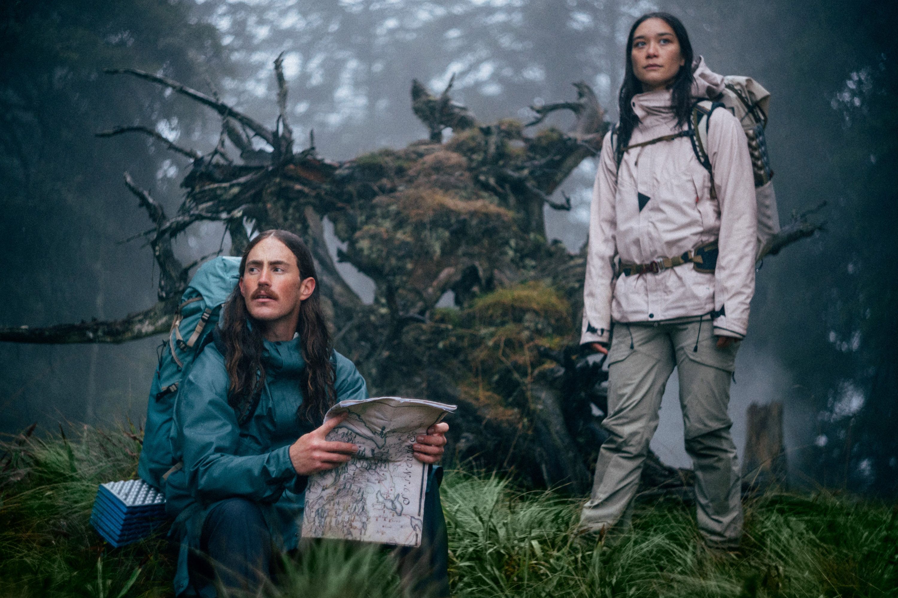 Man and woman in the woods reading a map