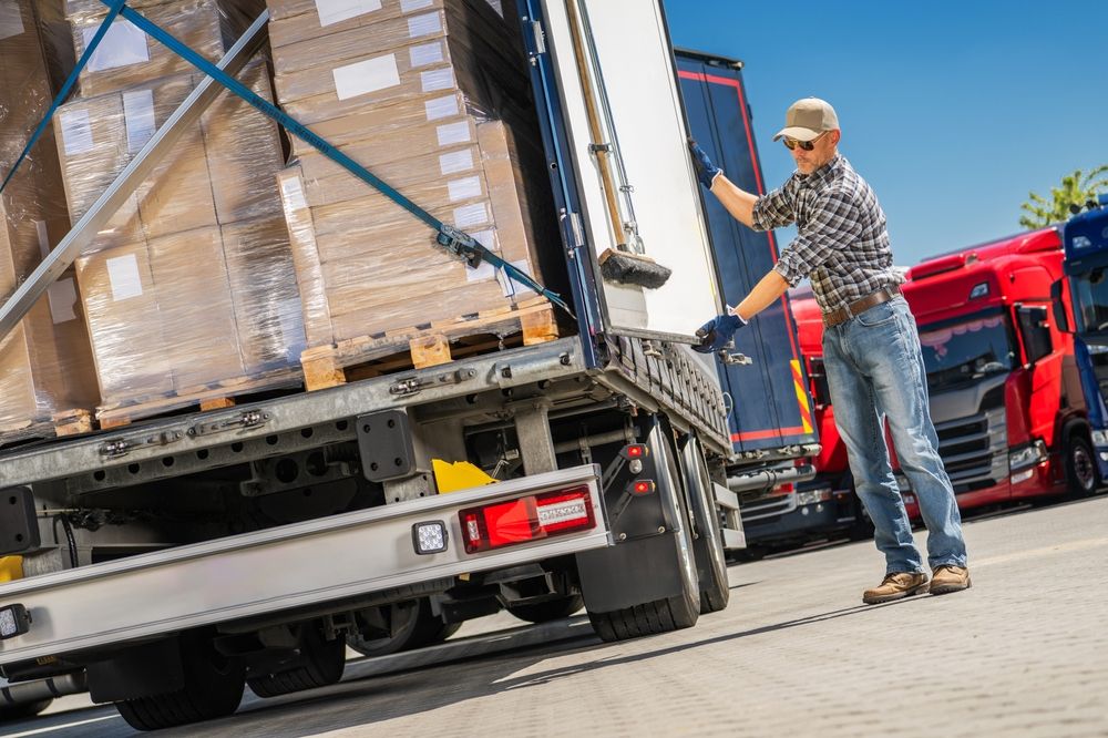 Worker unloading cargo from a commercial truck highlighting risks of improperly secured loads and potential truck accidents