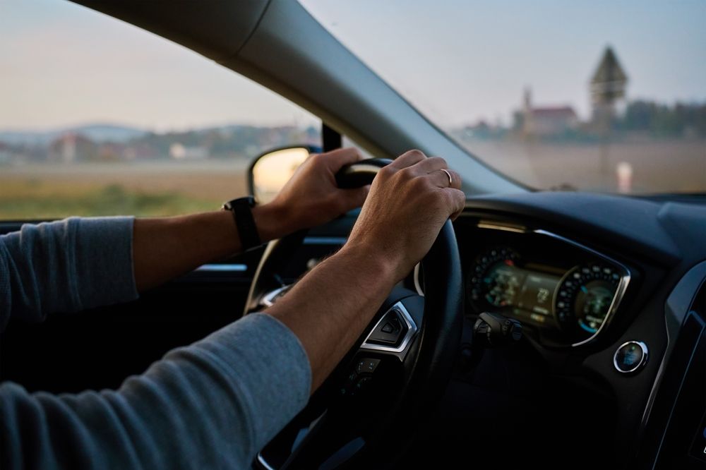 Driver holding the steering wheel during an early morning commute representing drowsy driving risks after Daylight Saving Time in Texas