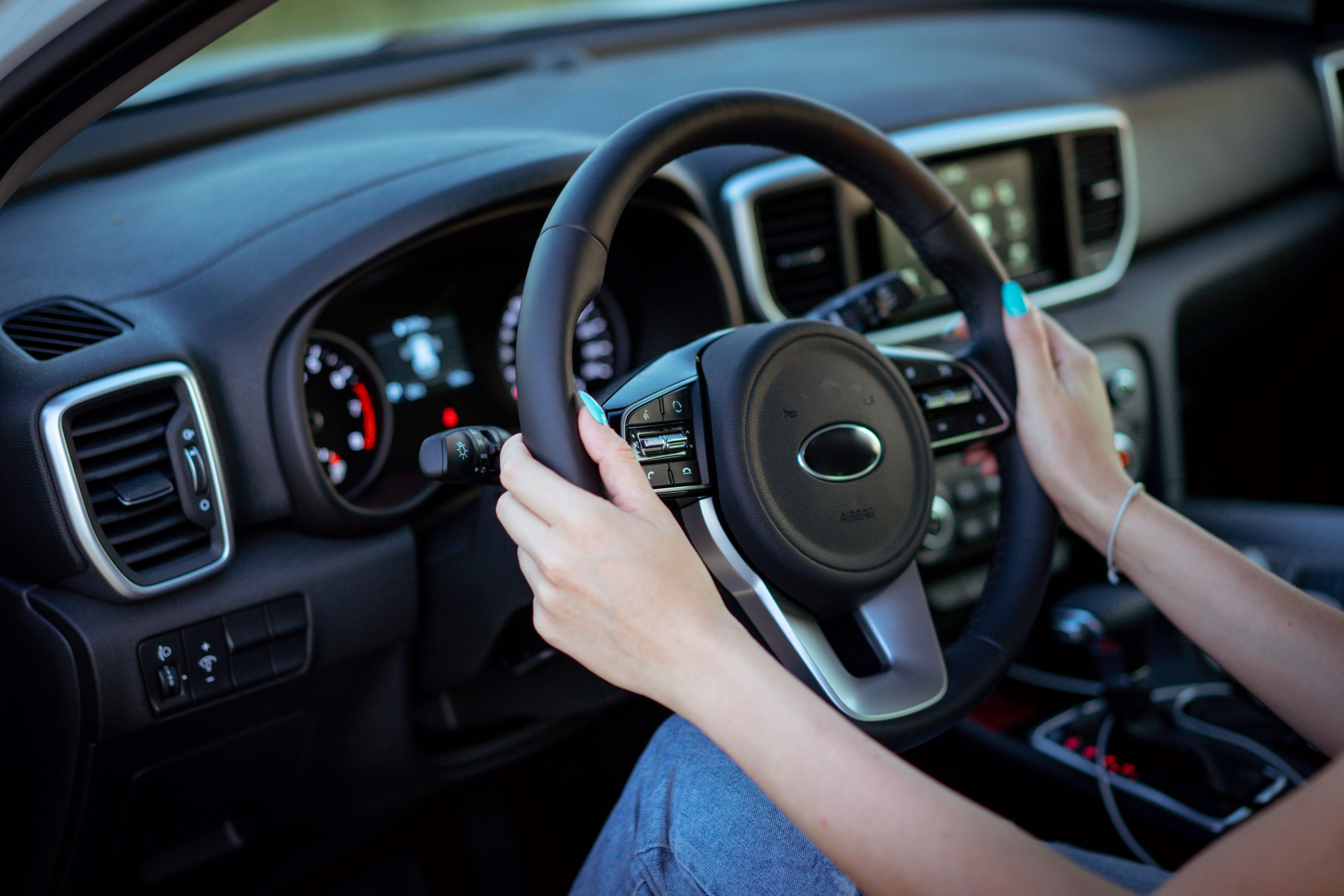 Conductora joven con las manos en el volante, que ilustra a los nuevos conductores adolescentes que regresan a calles concurridas durante el regreso a clases