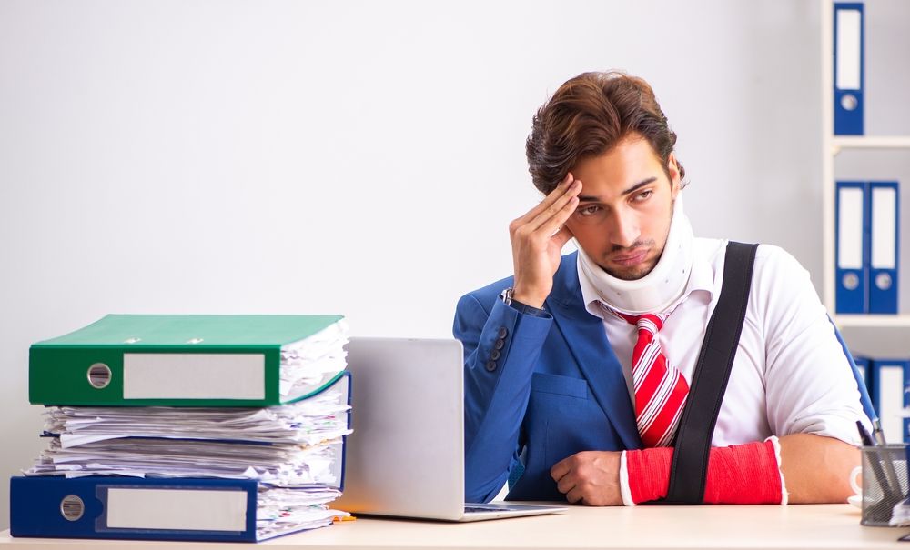 Hombre con collarín cervical sentado frente a expedientes médicos para probar una reclamación por lesiones tras un choque en Houston.