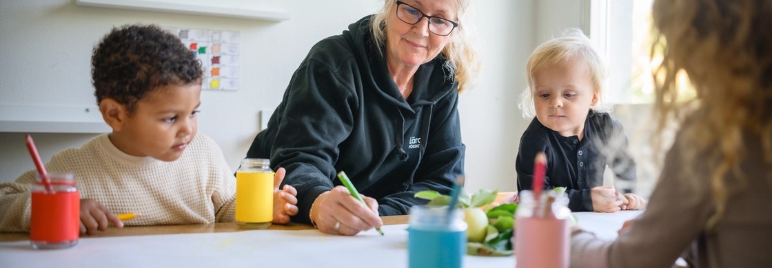 Pedagog ritar tillsammans med barn.