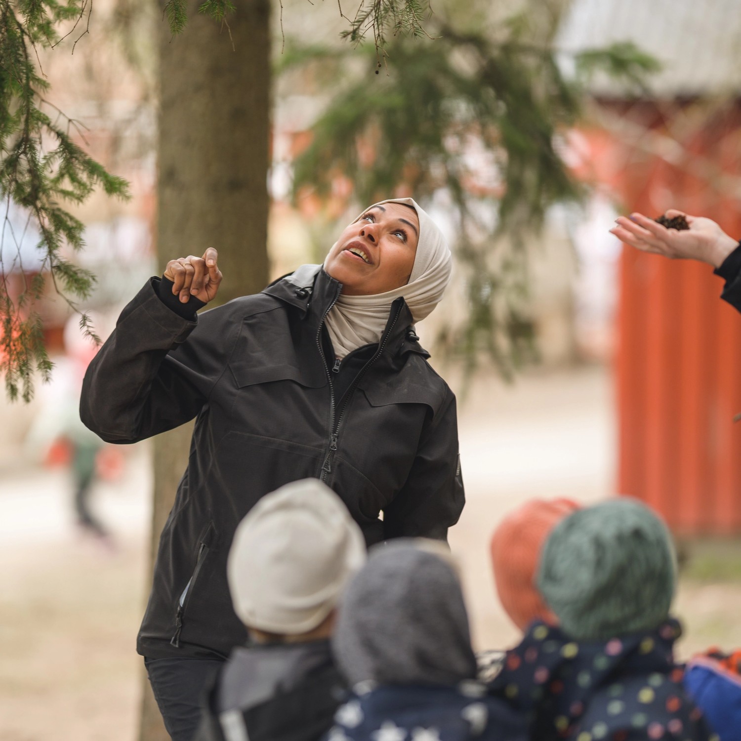 Pedagog och förskolebarn tittar på träd utomhus